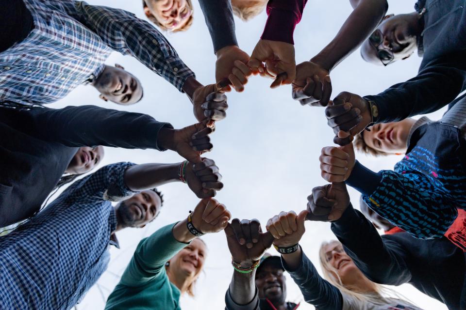 Eine Gruppe von Menschen steht im Kreis mit geballten Fäusten.