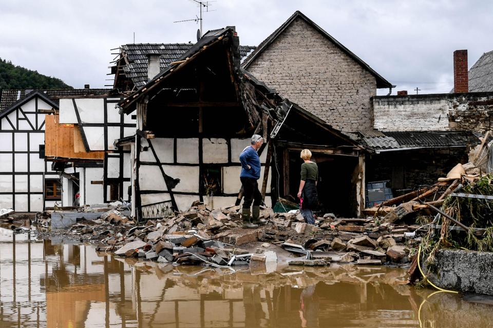 Hochwasserkatastrophe in Deutschland - Zwei Personen vor zerstörtem Haus