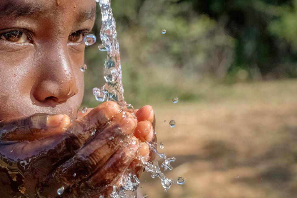 header WASH (a boy drinks water with his hands)
